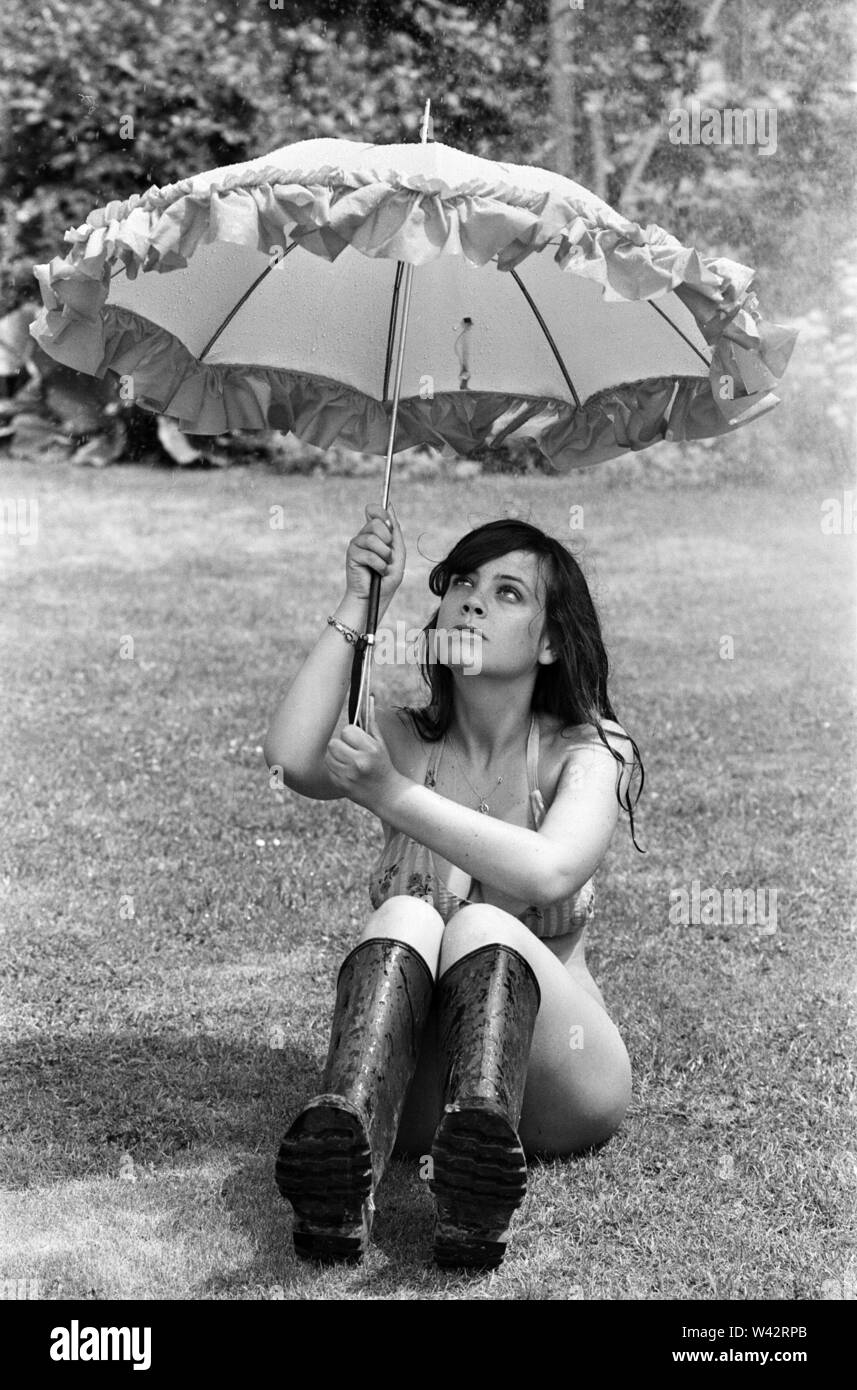 Hoping for a spot of rain to take her mind off the heatwave, this young lady, Jody, has to make do with the garden sprinkler to cool down, Reading, July 1976. Stock Photo