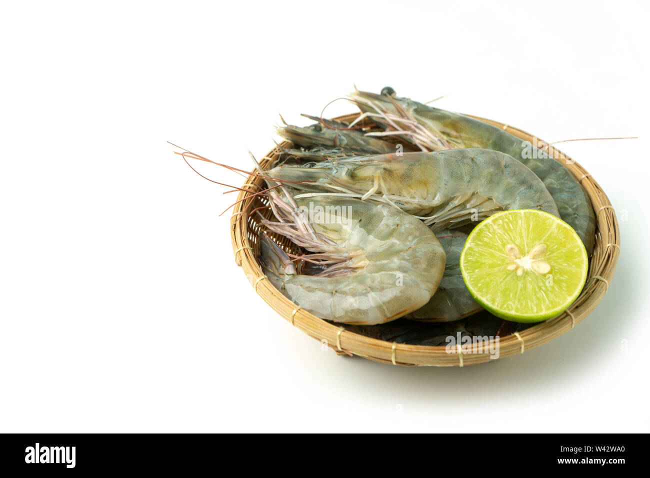 close up group of fresh raw pacific white shrimp and lemon in bamboo bowl on white background (Isolate background). Stock Photo