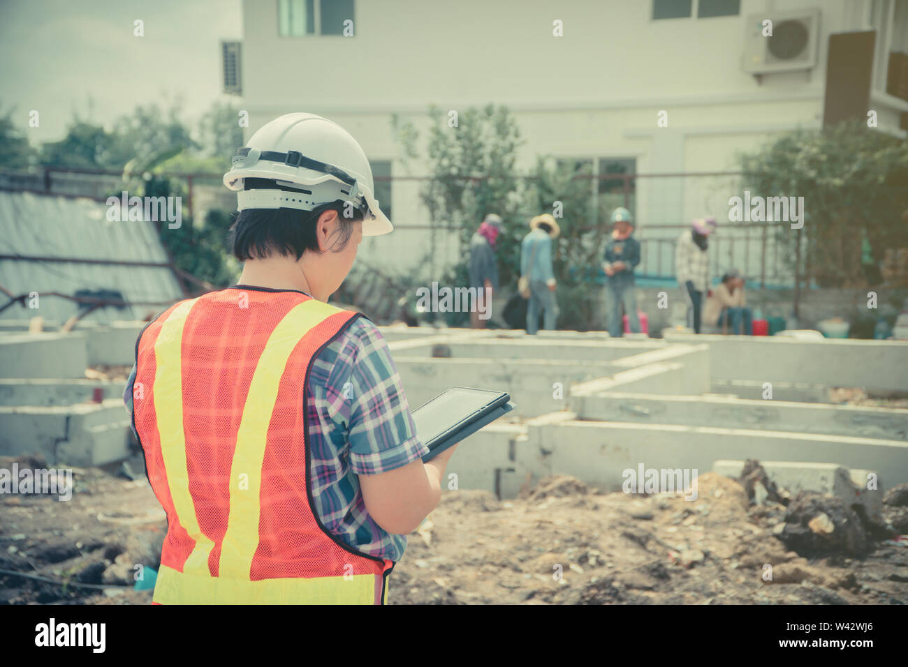 Asian women engineering holds a tablet for use in the inspection of construction sites for accuracy and in accordance with the plan. Concept of Equal Stock Photo