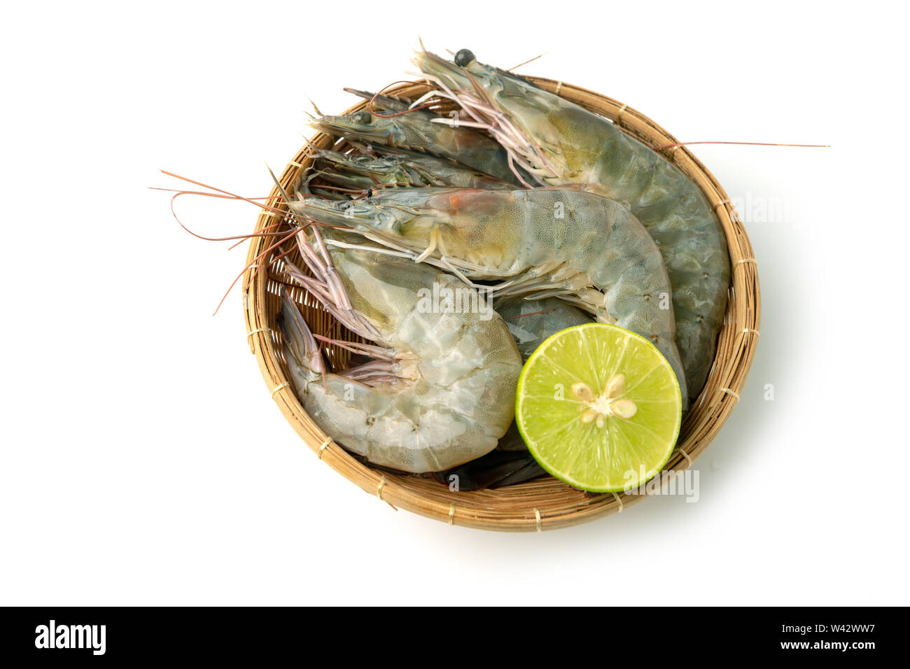 close up group of fresh raw pacific white shrimp and lemon in bamboo bowl on white background (Isolate background). Stock Photo