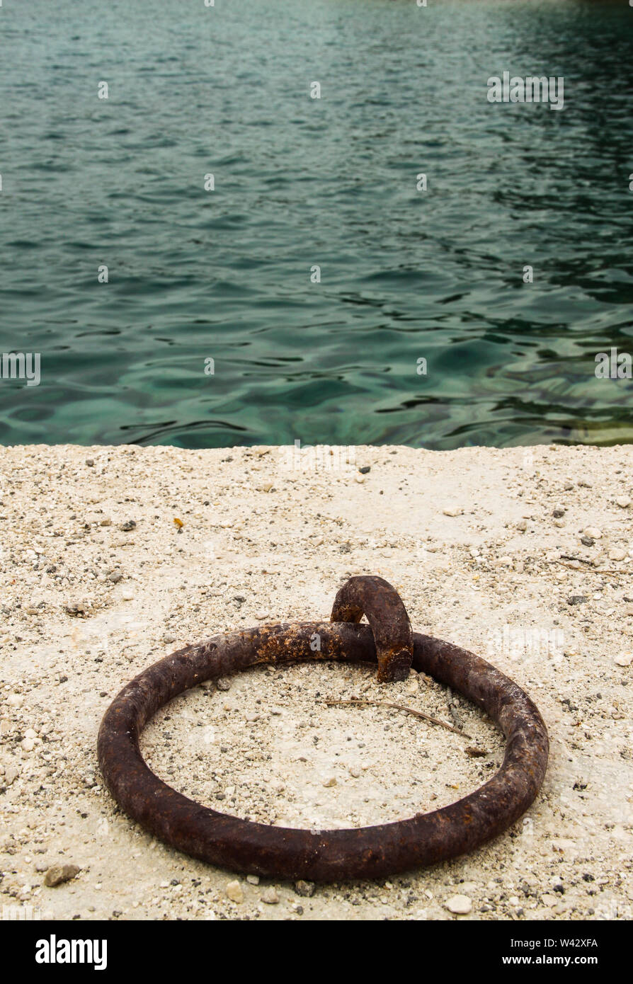 Metal mooring post on the edge of concrete bank of harbor Stock Photo