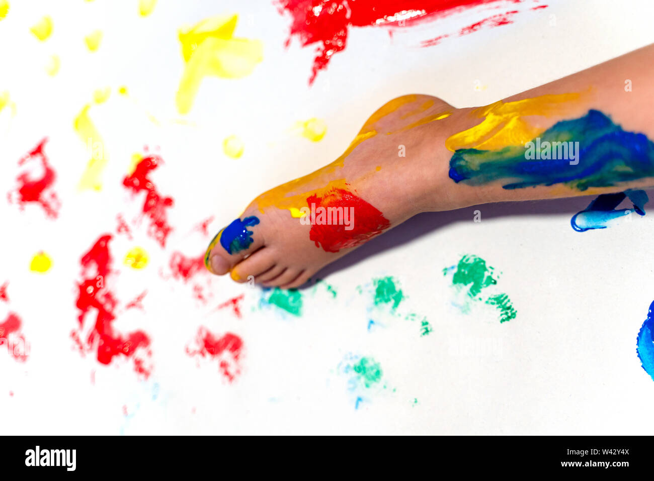 Toddler baby finger painting on a white paper on the floor Stock Photo