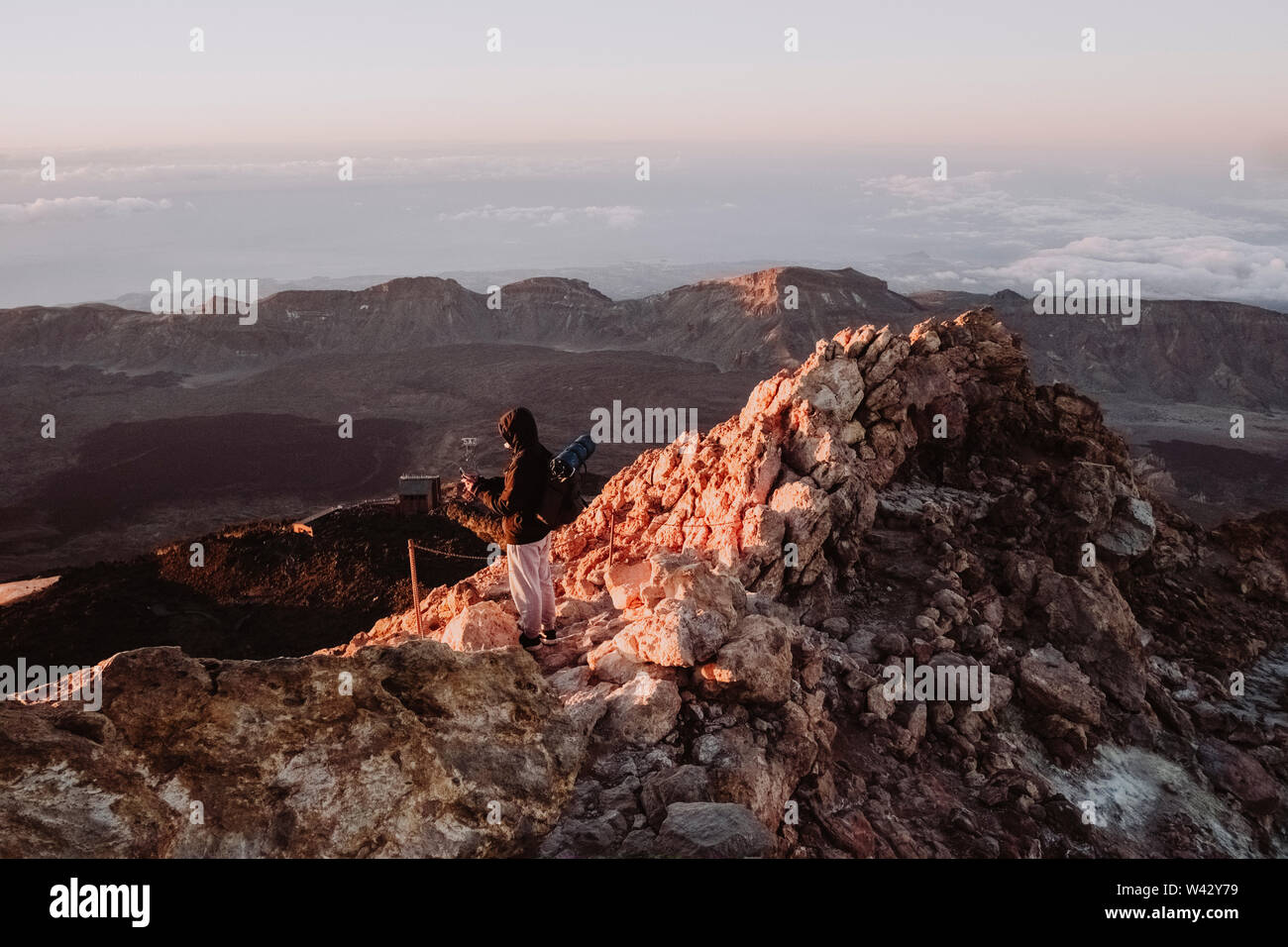 A male hiker watches sunrise from summit of El Teide Stock Photo