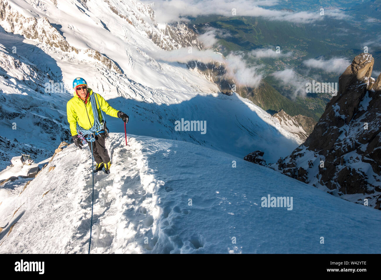 Alpinist pauses on a steep snow ridge high above the Chamonix Valley Stock Photo