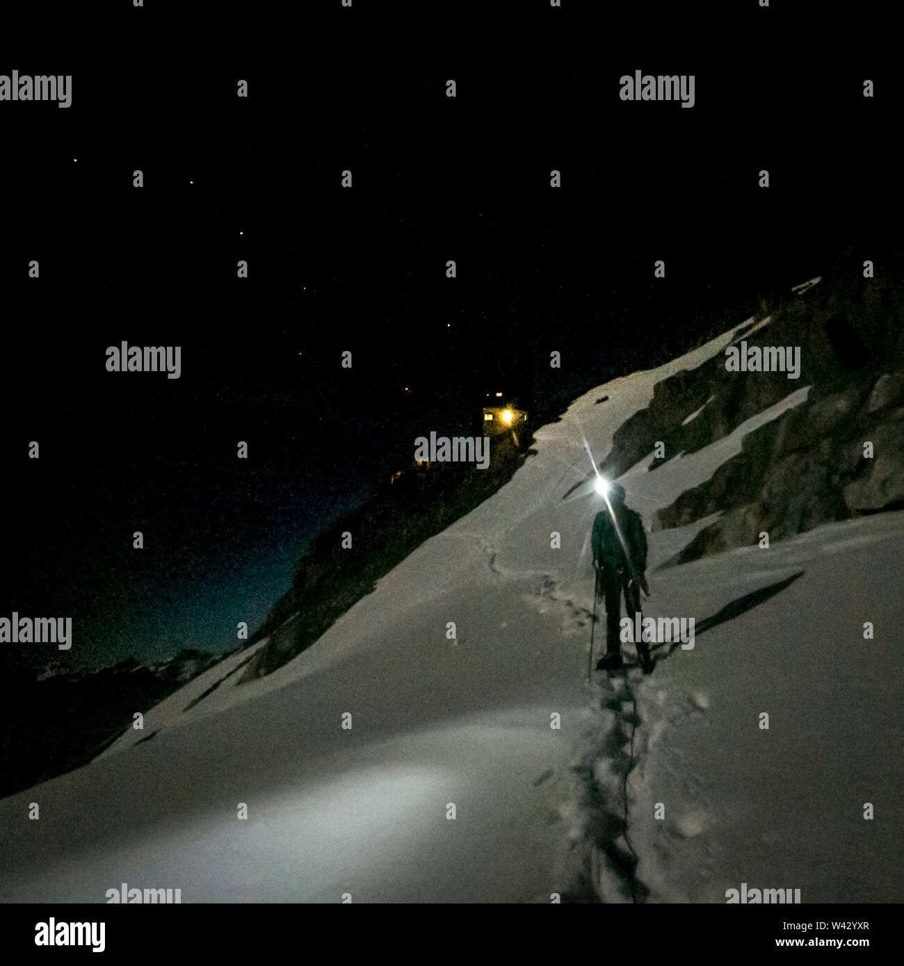 An alpinist shines his headlamp during an alpine start on a glacier Stock Photo