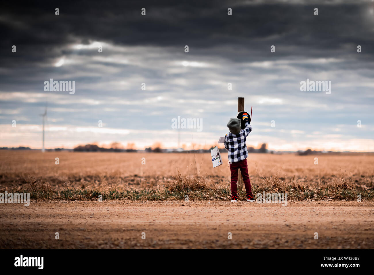 a small boy getting mail from a mailbox on a dirt road Stock Photo