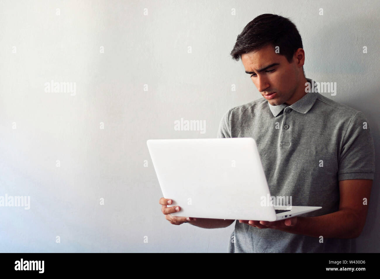 Man dressed in gray using a white laptop. Stock Photo