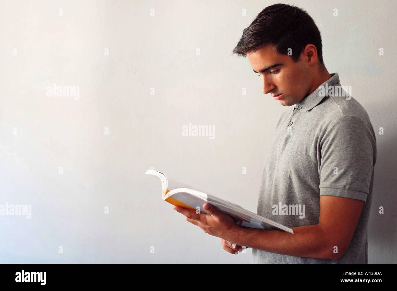 Man dressed in gray reading a book at home. Stock Photo