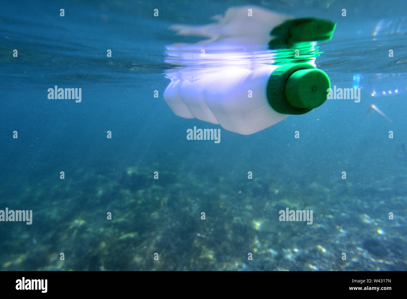 plastic bottle floating in the sea, photo underwater with the seabed