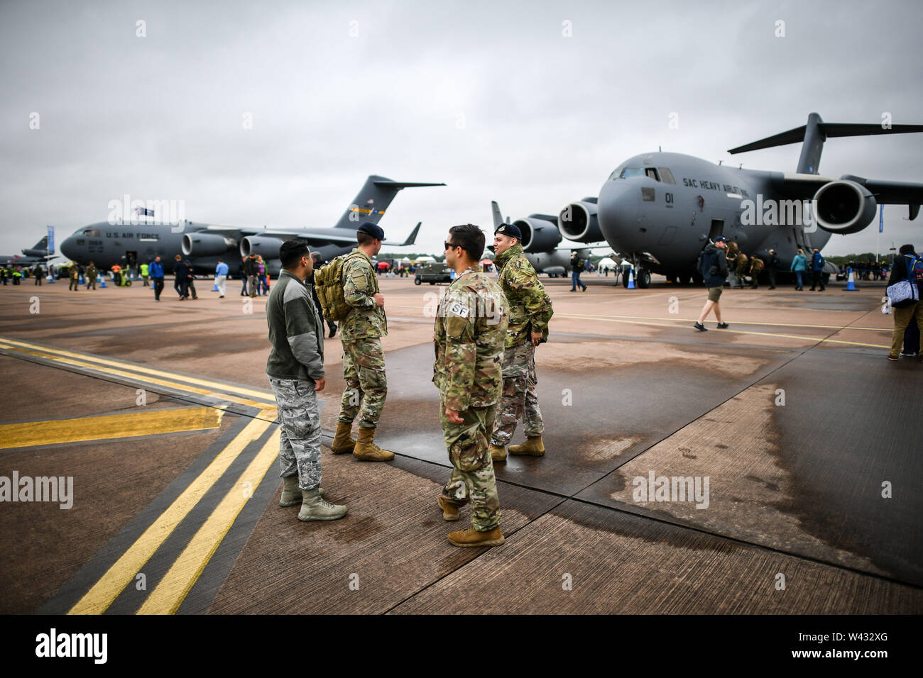 Military personnel chat in the static display aircraft area at the Royal International Air Tattoo, RAF Fairford, as bad weather including strong winds, low cloud and rain have grounded many of the planned air displays. Stock Photo