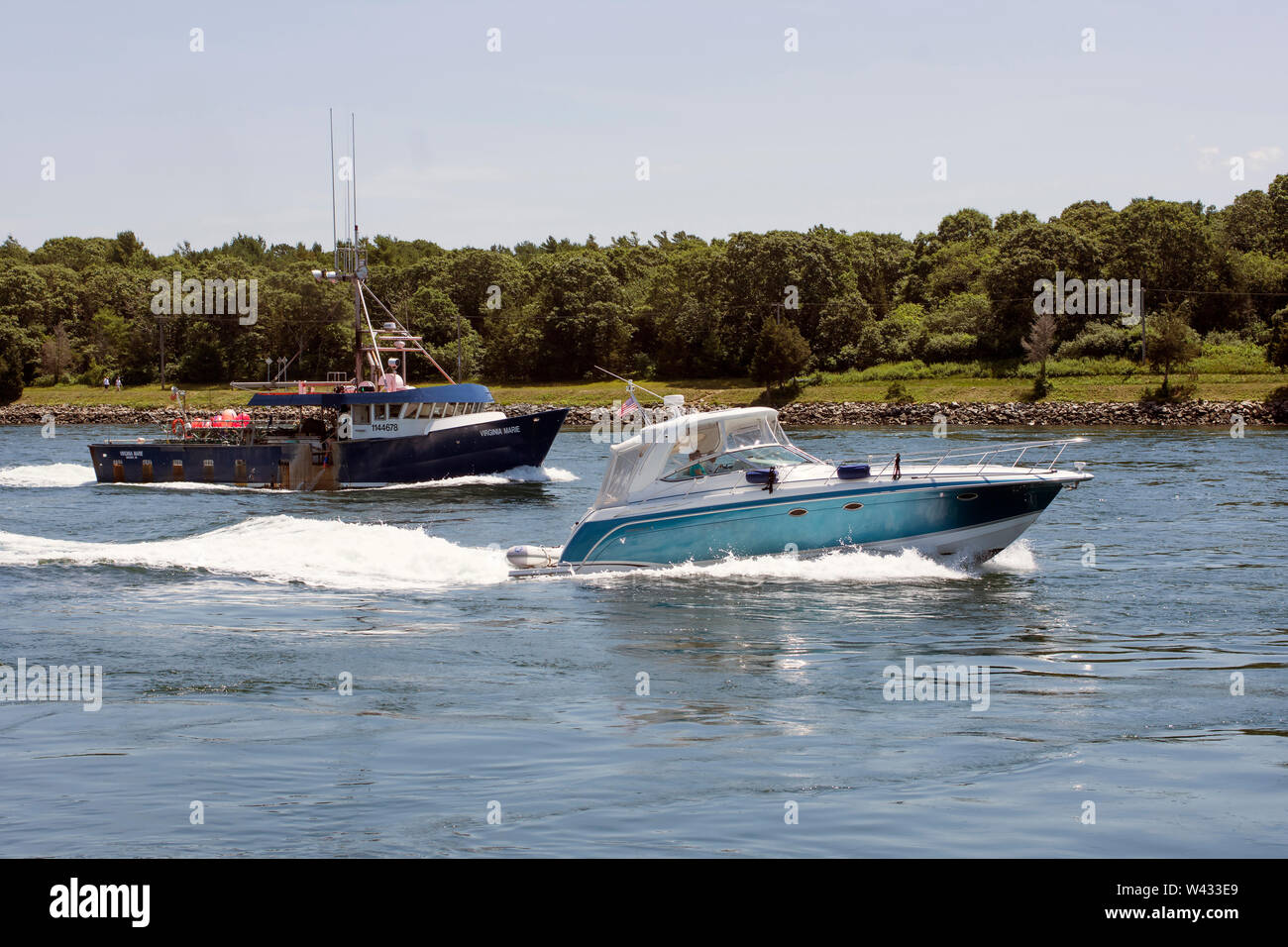 A private yacht passes a fishing boat in the Cape Cod Canal, in Bourne