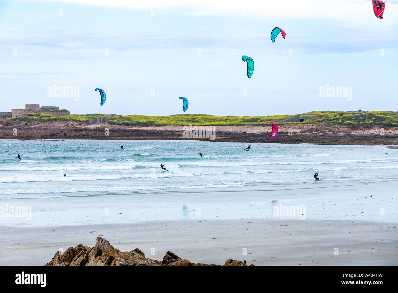 Kitesurfing in Vazon Bay, Guernsey, Channel Islands UK - Fort Hommet is in the background Stock Photo