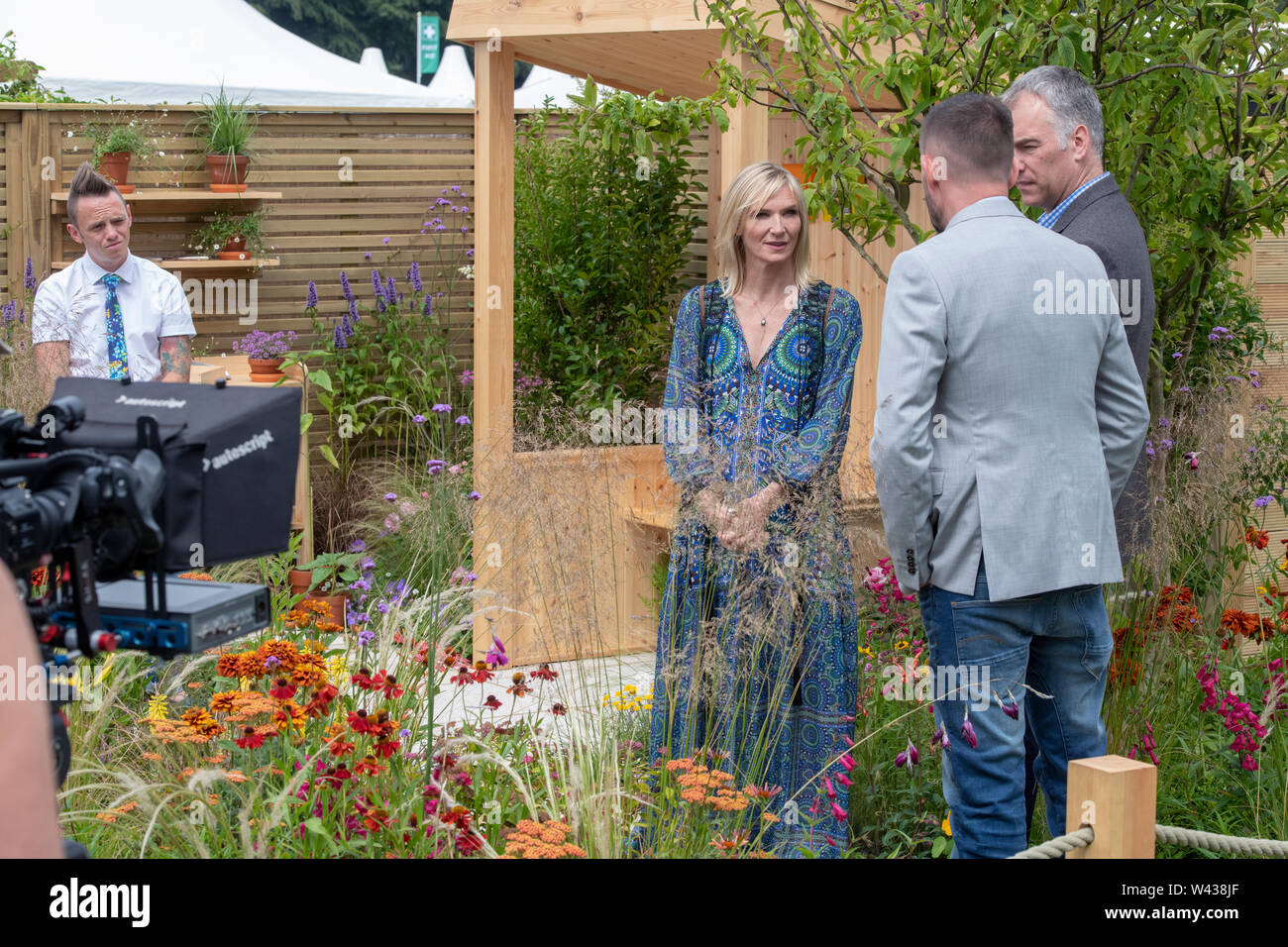 Jo Whiley  doing a piece to camera in the BBC North West Tonight Sunshine Garden In Memory of Dianne Oxberry at RHS Tatton Park flower show 2019. UK Stock Photo