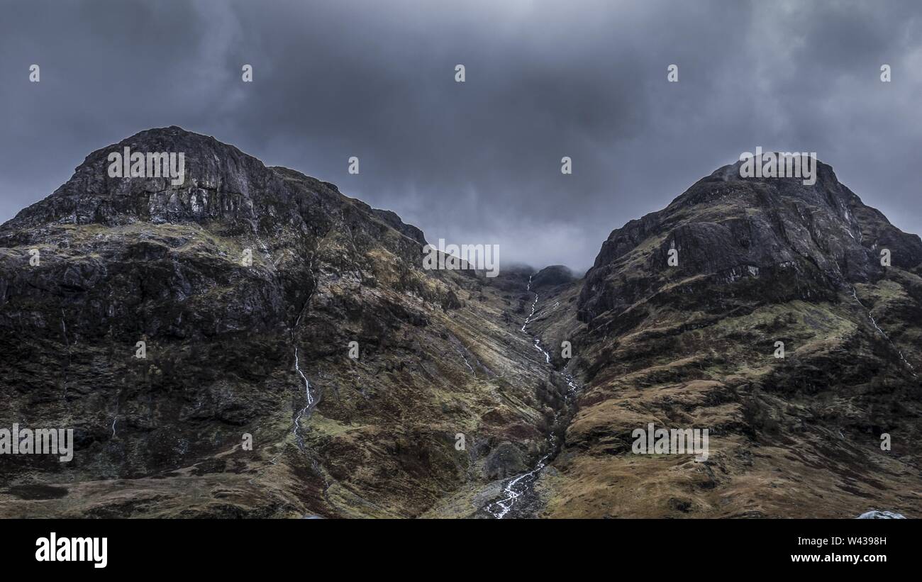 A Beautiful Low Angle Shot Of Rocky High Mountains Under A Grey Stormy Sky At Daytime Stock Photo Alamy A Beautiful Low Angle Shot Of Rocky High Mountains Under A Grey Stormy Sky At Daytime Stock Photo Alamy