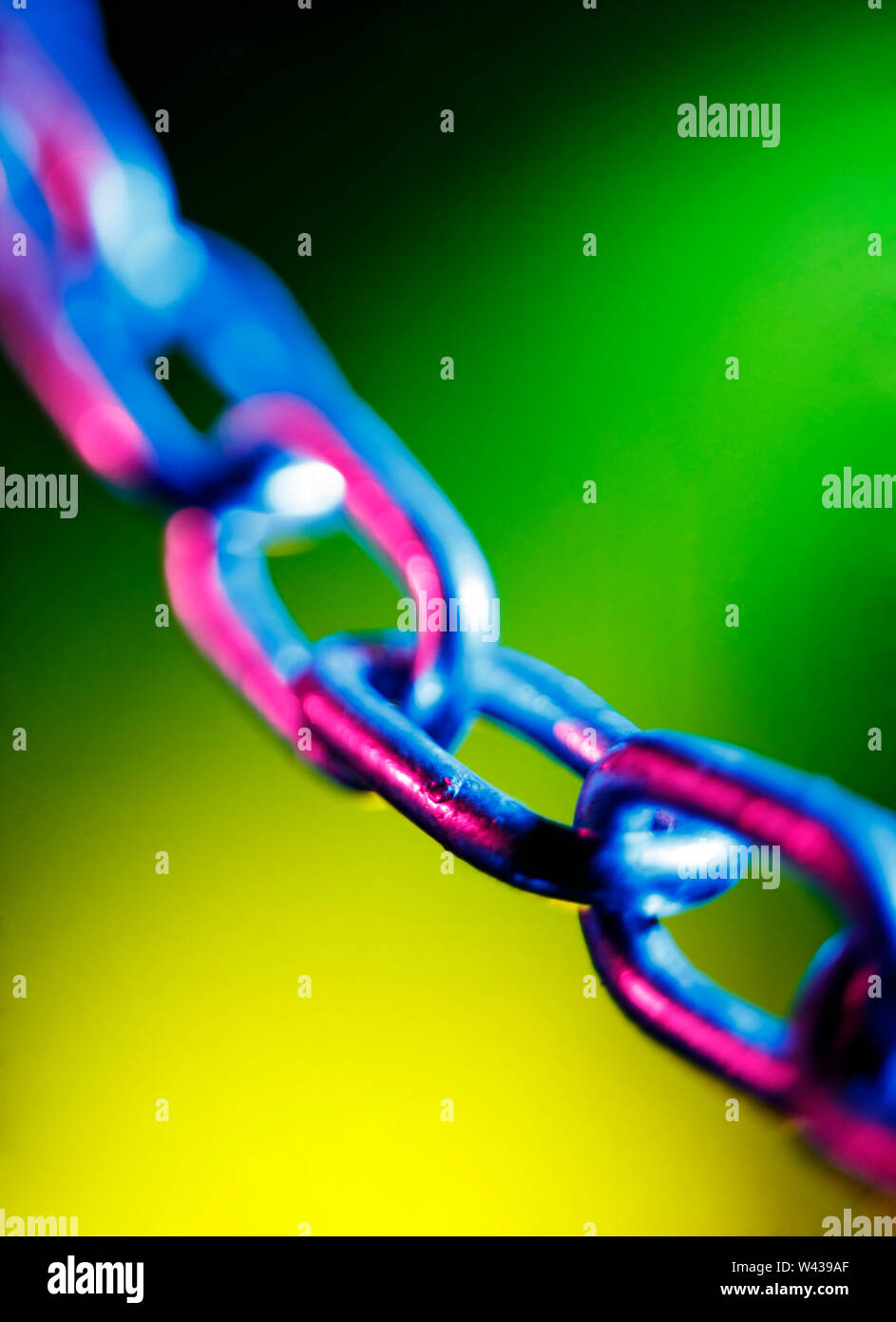 Abstracted short depth of field image of chain links, on a colourful green and yellow background Stock Photo