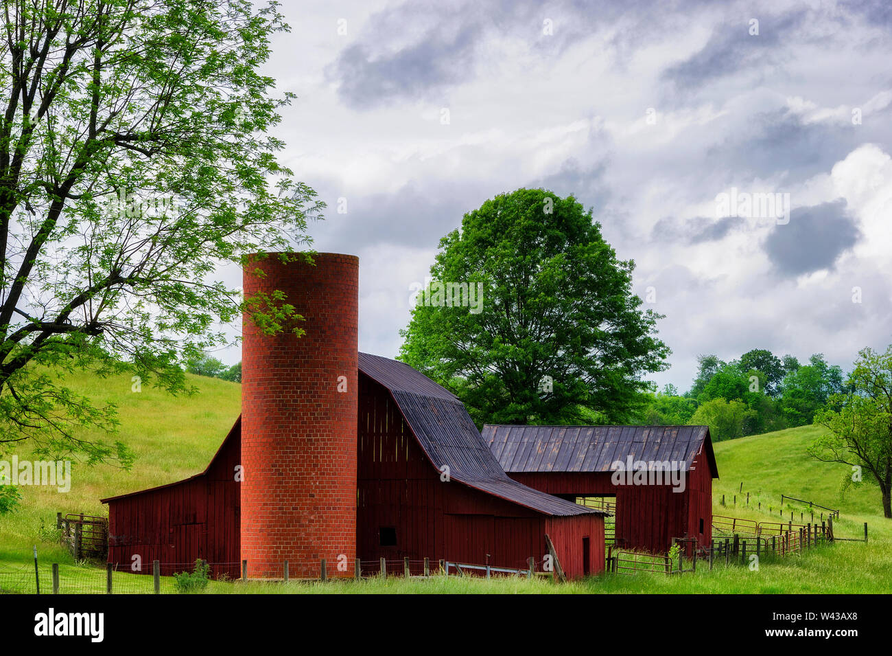 Country side view of a red barn and brick silo on rolling hills in Virginia. Stock Photo