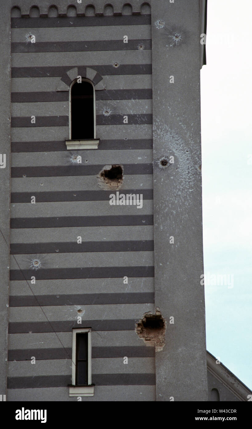 12th April 1993 During the Siege of Sarajevo: bullet and shell holes in the clock tower of the Church of the Holy Trinity on Sniper Alley (Zmaja od Bosne), in the Dolac Malta area of the city. Stock Photo