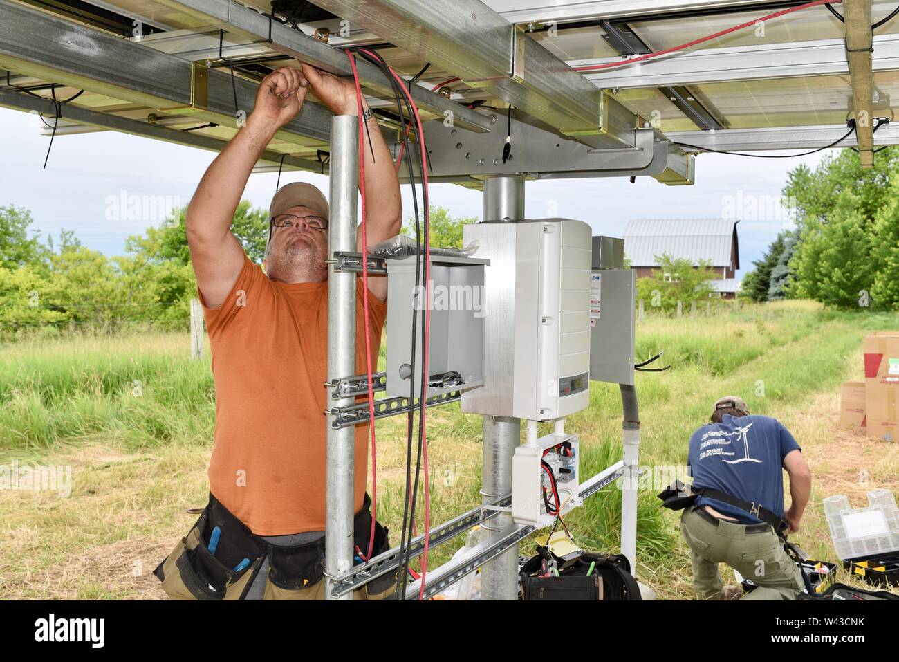 Certified electricians installing a solar electric (photovoltaic) system in a field to generate electricity from the sunlight, Wisconsin, USA Stock Photo