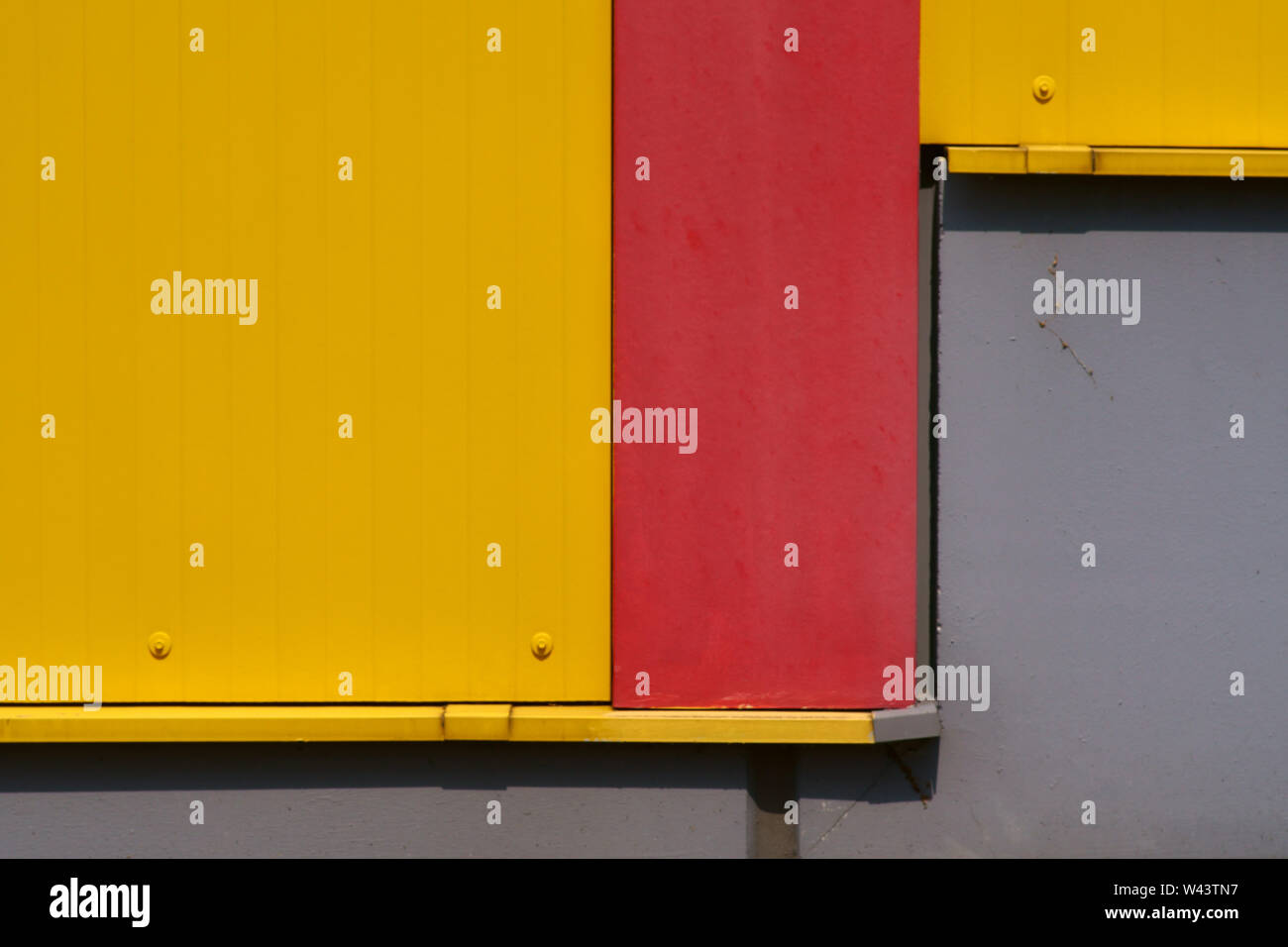 The side view of a color-intensive corrugated iron wall of a shopping center with bars in front of the wall. Stock Photo