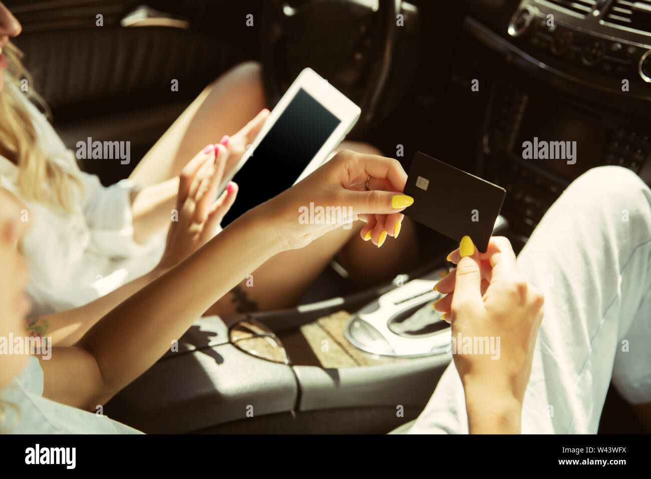 Young lesbian's couple preparing for vacation trip on the car in sunny day. Women sitting and ready for going to sea, riverside or ocean. Concept of relationship, love, summer, weekend, honeymoon. Stock Photo
