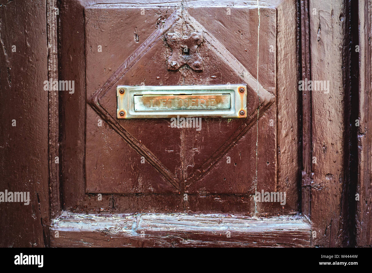 The letter sign is a symbol of the mailbox attached to the brown wooden door of the house. Outdated methods of correspondence. Stock Photo