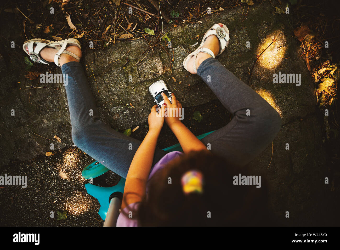 Little girl in park playing with car toy Stock Photo - Alamy