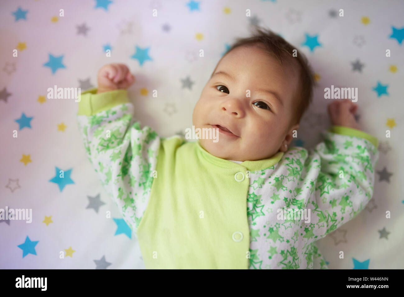 Portrait of baby lay in bed in green creamy colors Stock Photo