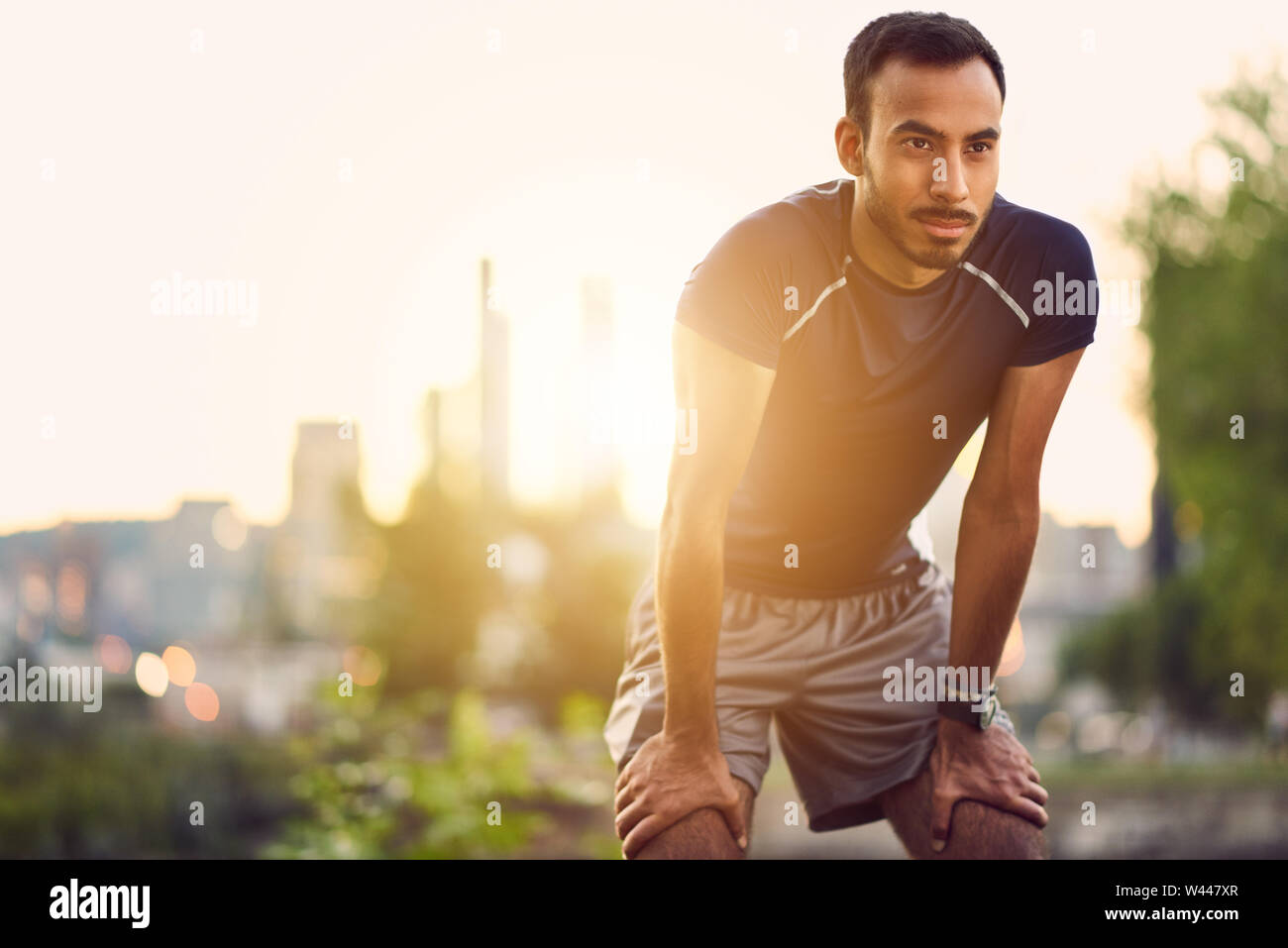 Portrait of a indian male athlete running at dusk with sunset on the city of Montreal in the background Stock Photo