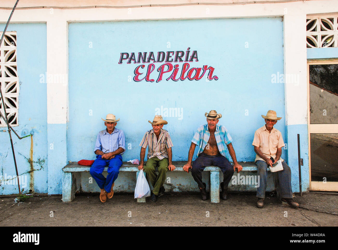 Four Cuban men wearing cowboy hats sit in front of a bread making store in Viñales, Cuba Stock Photo