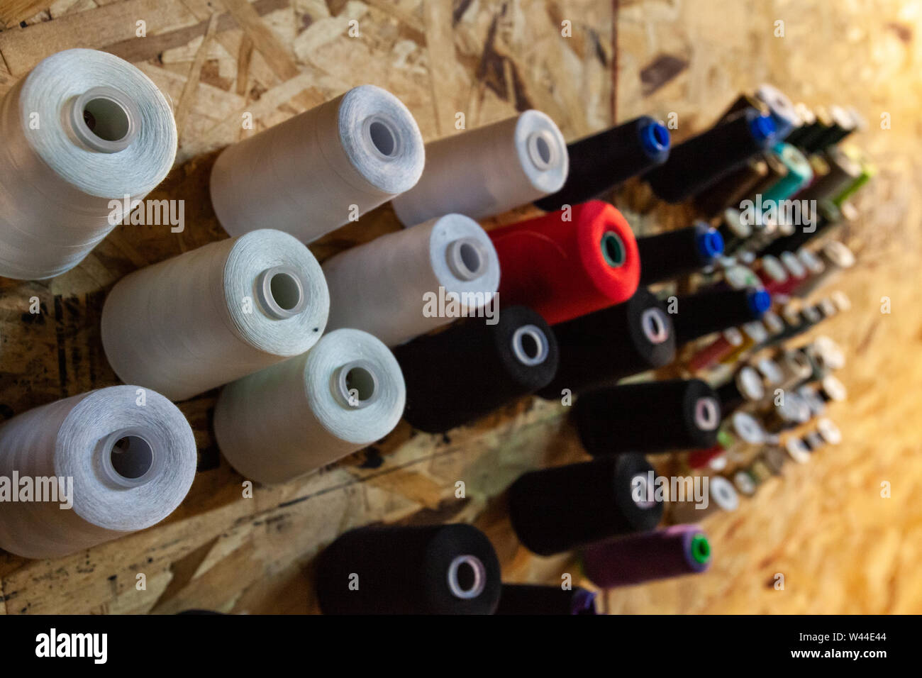 Various colors and grades of thread spools are viewed close-up, hung on ...
