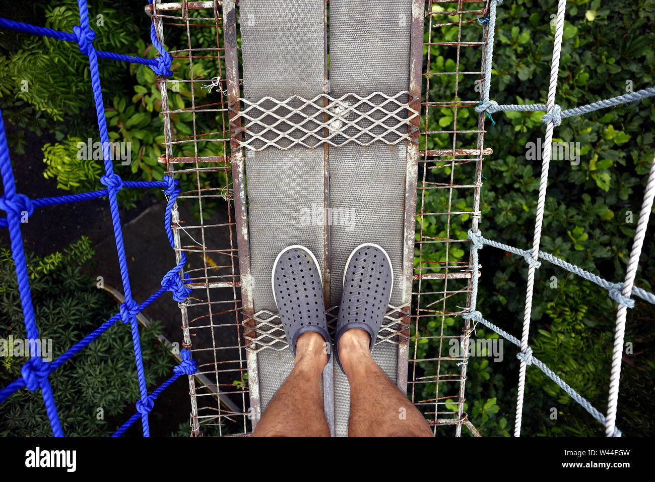 First person point of view of a man looking at his feet while standing on a  hanging bridge Stock Photo - Alamy