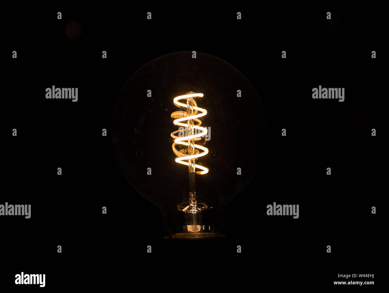 Lightbulb on dark background with bright spiral wire Stock Photo