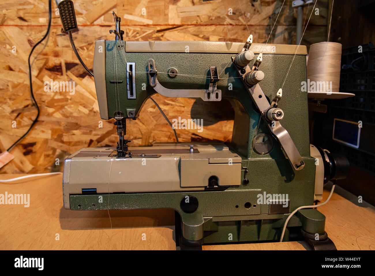 A closeup and side profile view of a retro sewing machine with thread spool inside a rustic