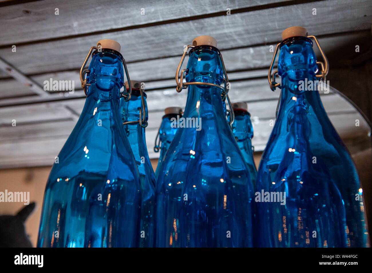 Decorative blue glass bottles are seen up close, on a shelf inside an