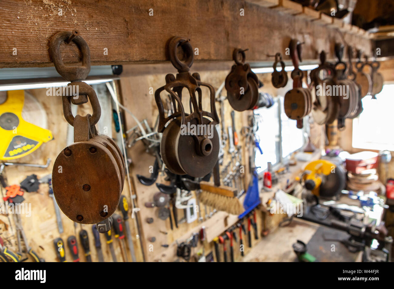 A closeup view on old-fashioned lifting wheels hanging over a metal workshop. Part of a block and tackle system used with ropes to lift heavy objects. Stock Photo