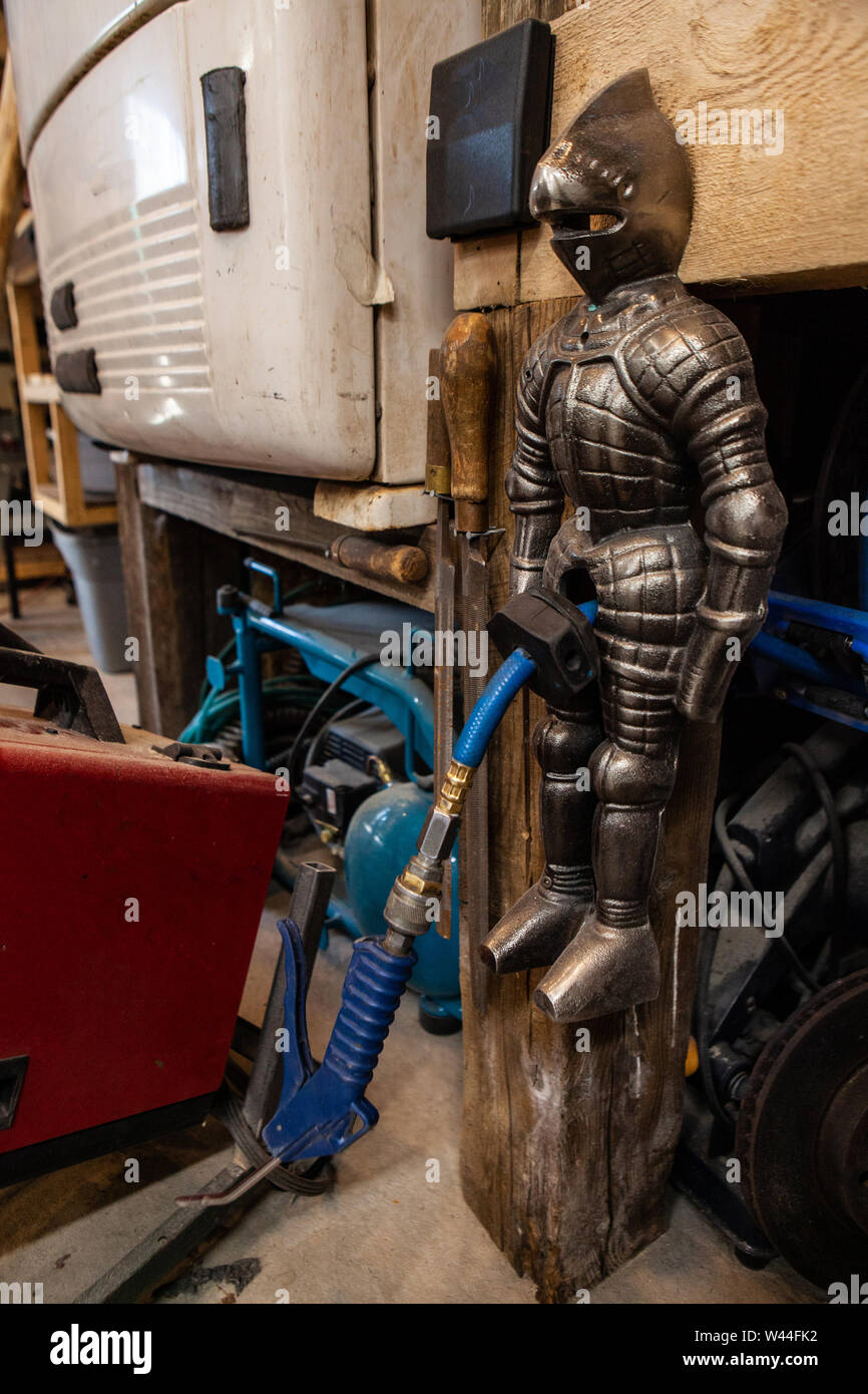 A closeup view of a small metal sculpted soldier figure used for storing the hose from an air compressor machine. Humorous object with hose in pelvic area. Stock Photo