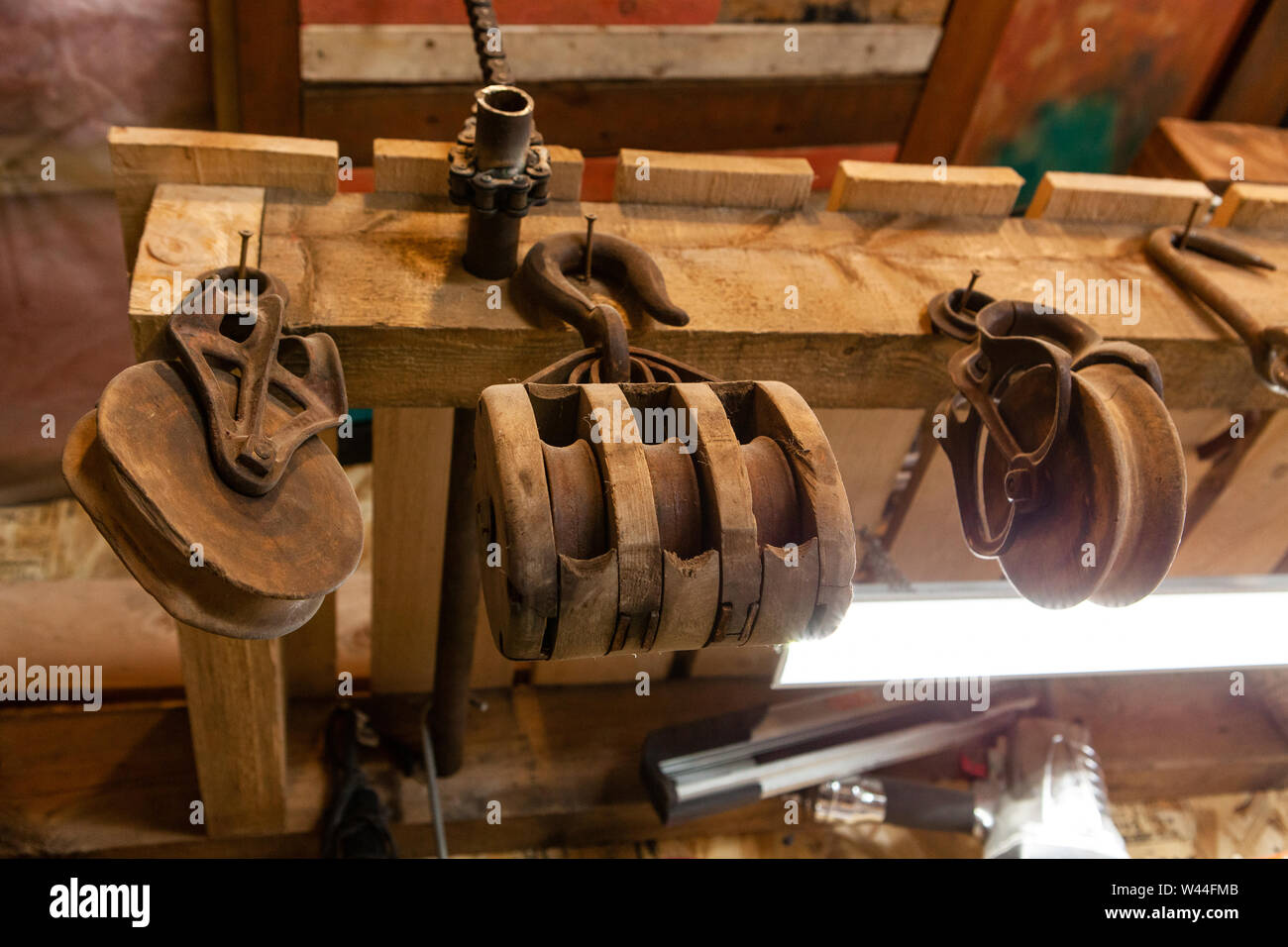A low angle view of vintage lifting wheels hanging inside a rustic workshop. Traditional lifting mechanisms used in a block and tackle system. Stock Photo