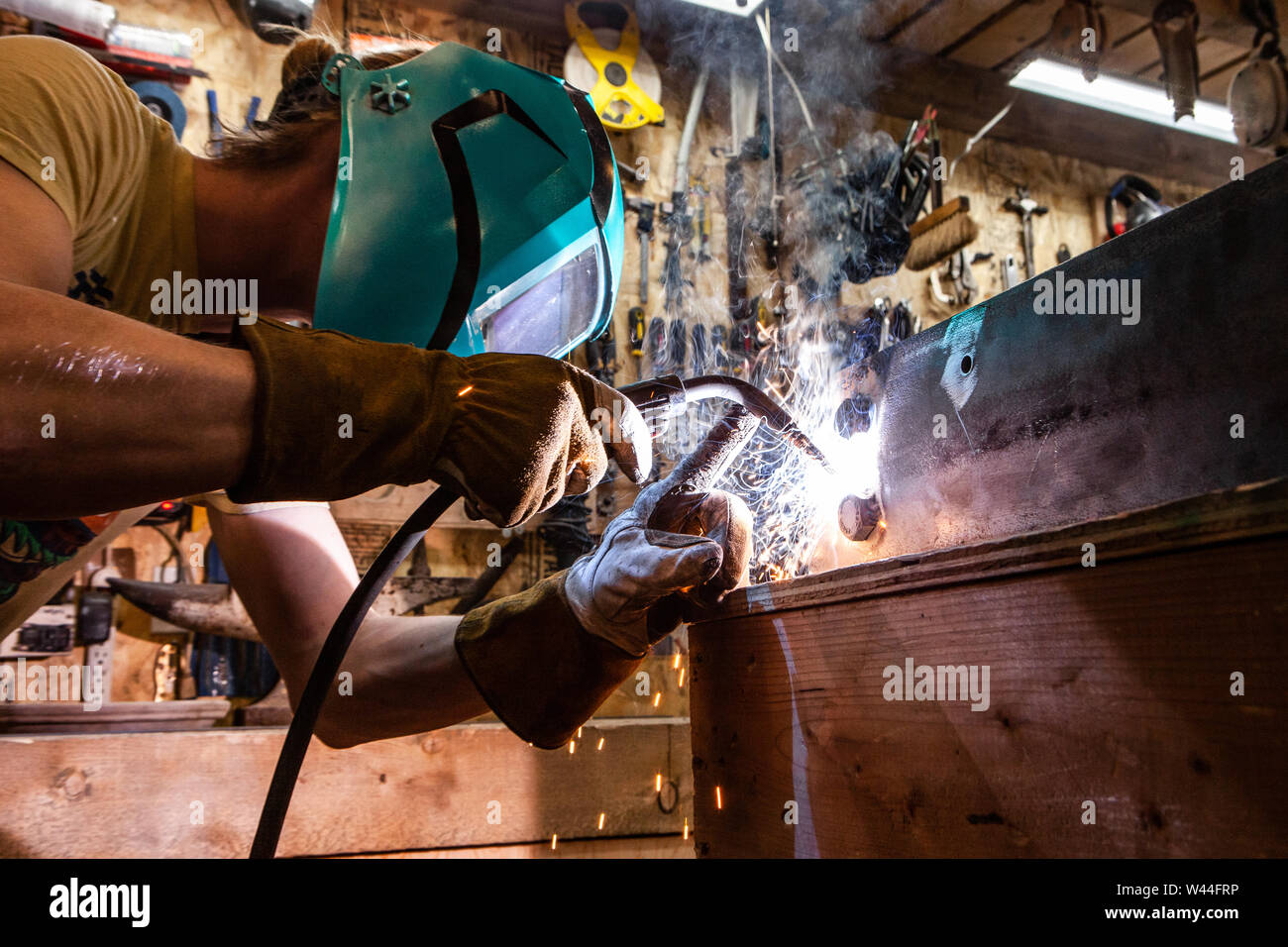 A closeup view of a skilled tradesman operating a metal inert gas welder to join the corners of two steel beams. Process of a metalworker at work. Stock Photo