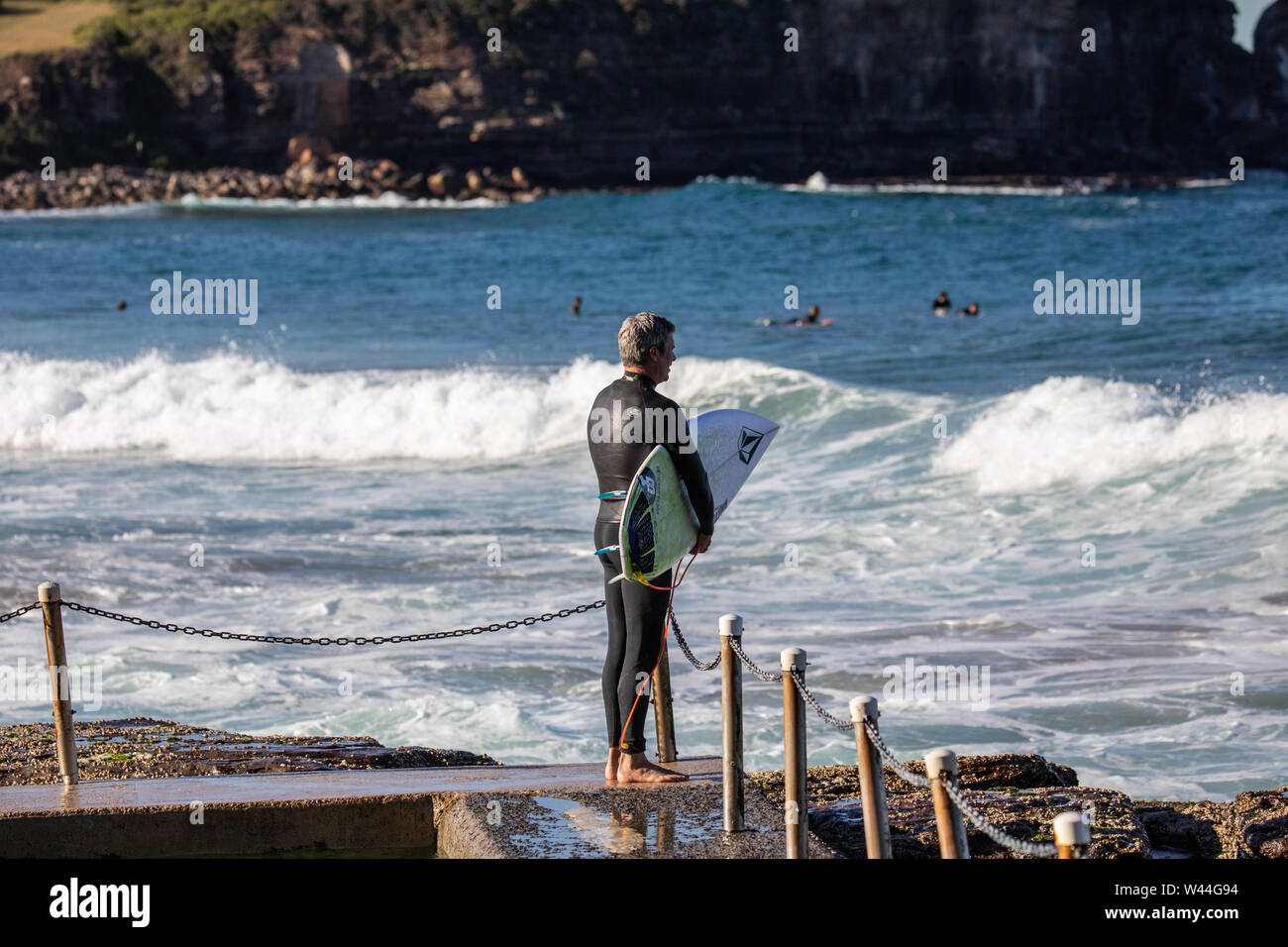 Middle aged australian make in wetsuit heads to the ocean for a surf