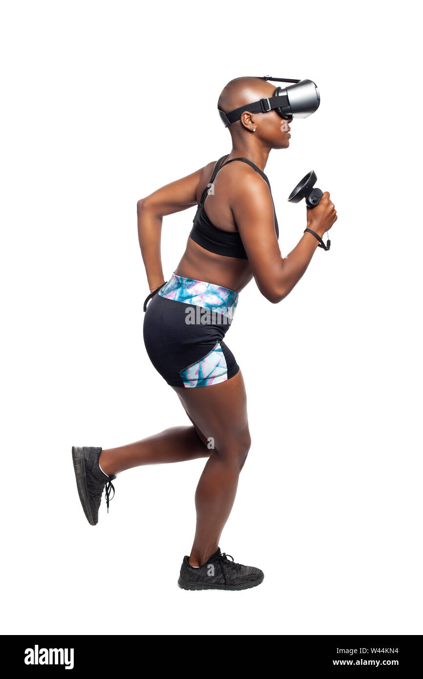 Black African American female running in VR while wearing a virtual reality headset for training or playing a video game.  Depicts technology and spor Stock Photo