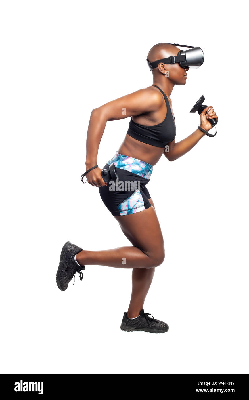 Black African American female running in VR while wearing a virtual reality headset for training or playing a video game.  Depicts technology and spor Stock Photo