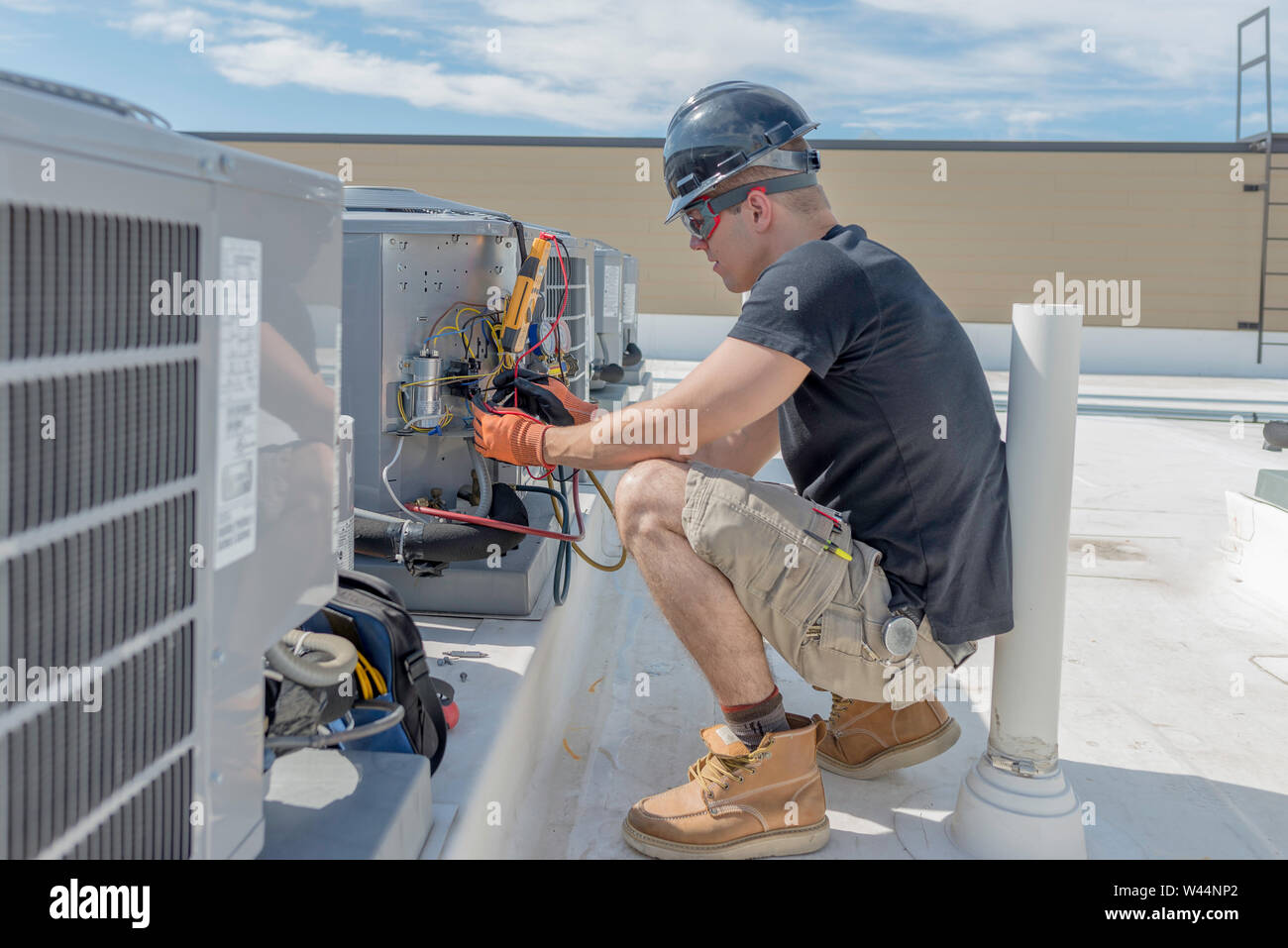 Hvac technician working on a condenser with the electrical access panel