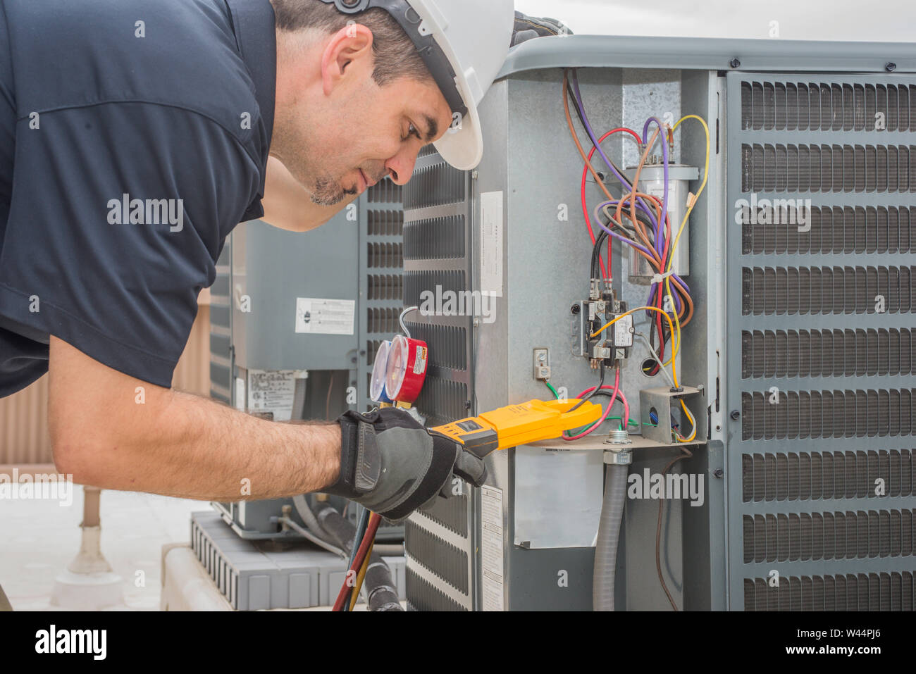 Professional hvac technician measuring amperage on an air conditioner