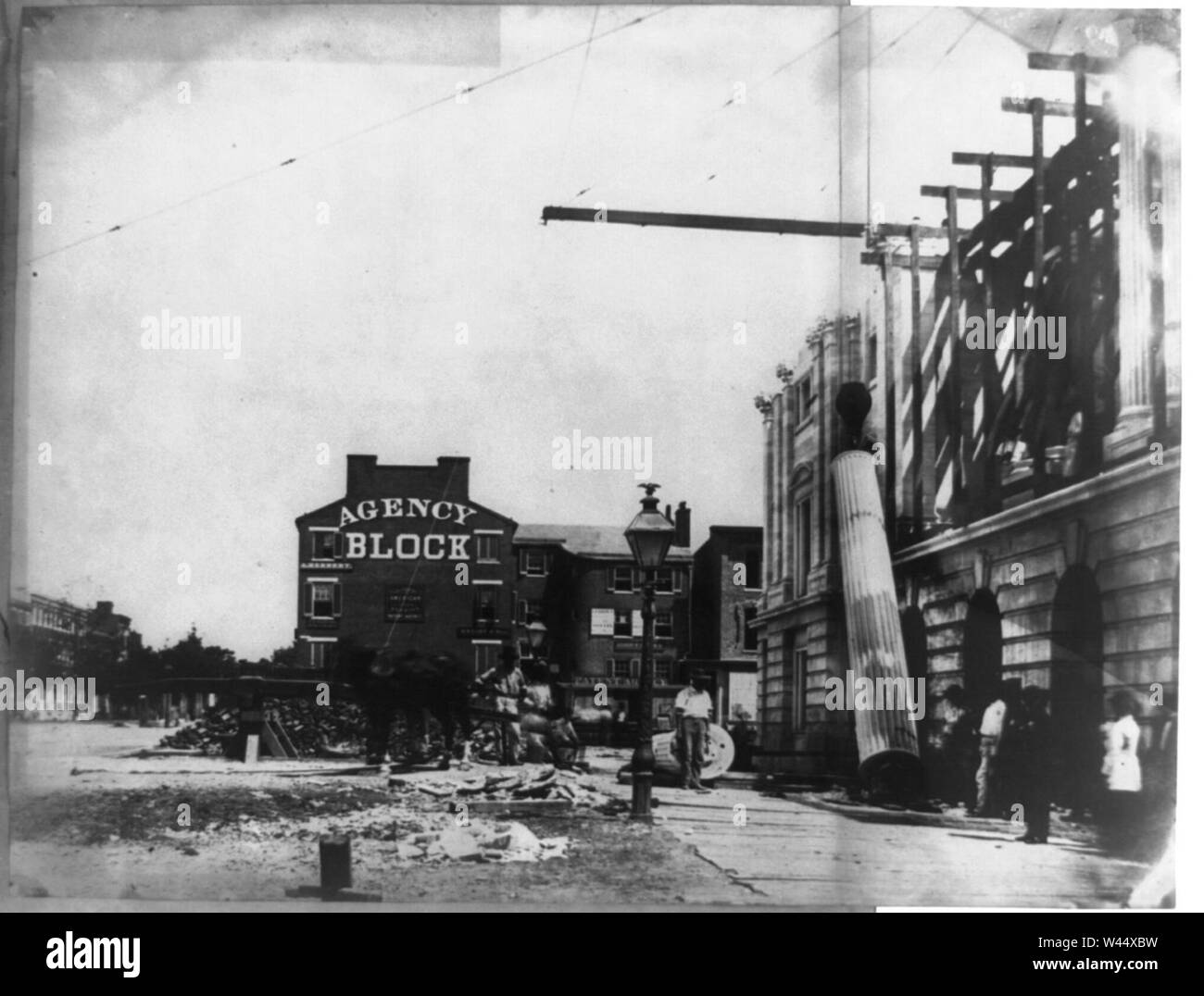 Column being raised into position, U.S. Post Office, with building ...