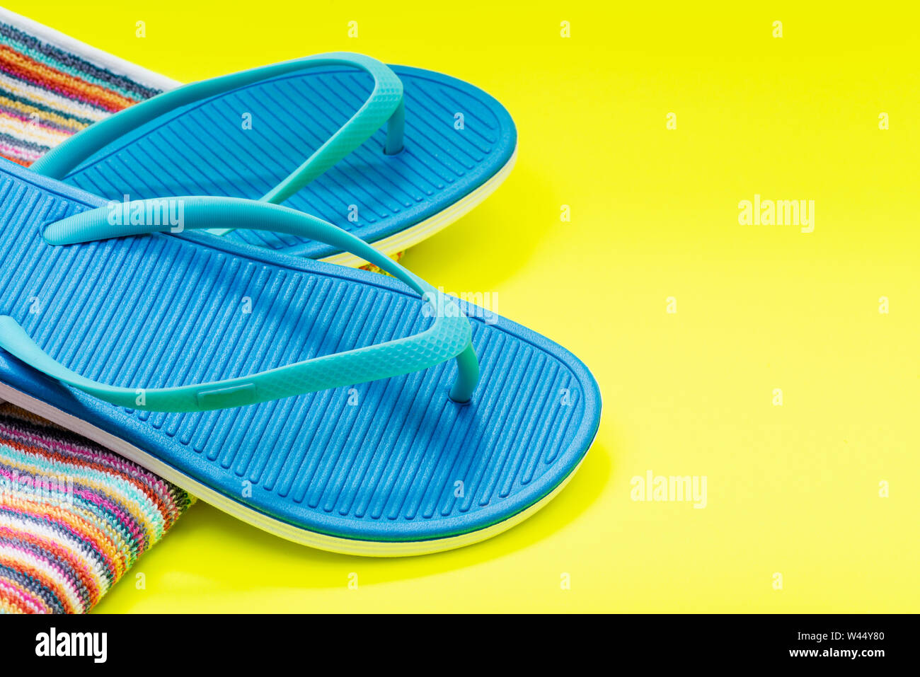 Folded Colorful Striped Organic Cotton Beach Towels and Blue Flip Flops ...