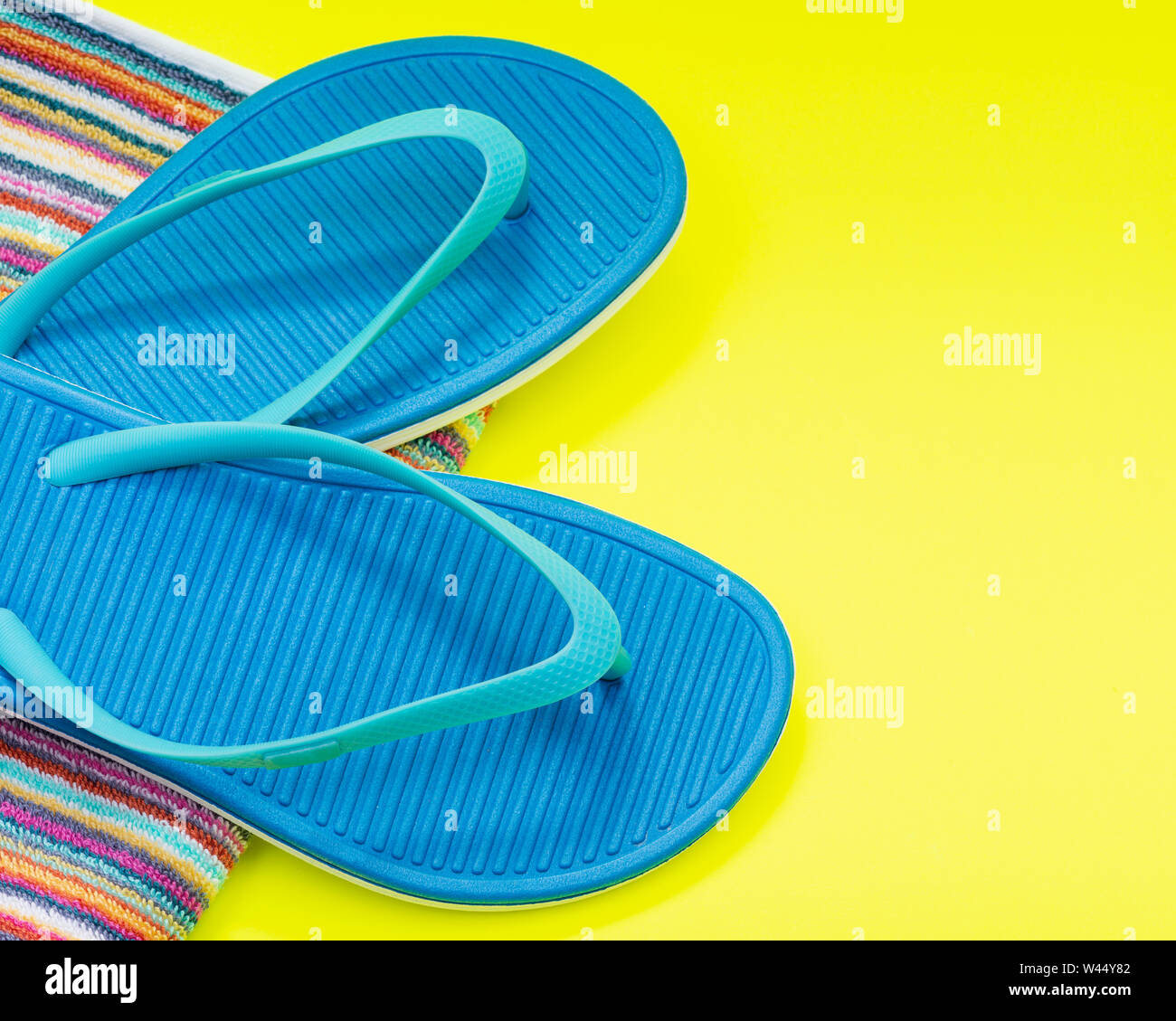 Folded Colorful Striped Organic Cotton Beach Towels and Blue Flip Flops ...
