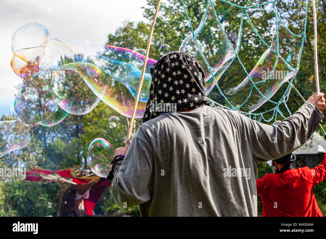 Iridescent bubbles are seen coming from a structure crafted with bamboo and string, held by a pagan during a celebration of native traditions. Stock Photo