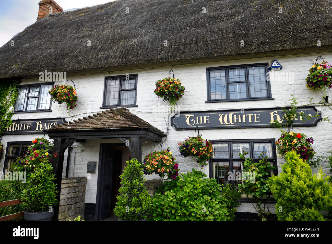 Facade of the White Hart Pub and Inn in Wroughton England with flower garden and thatched roof Stock Photo