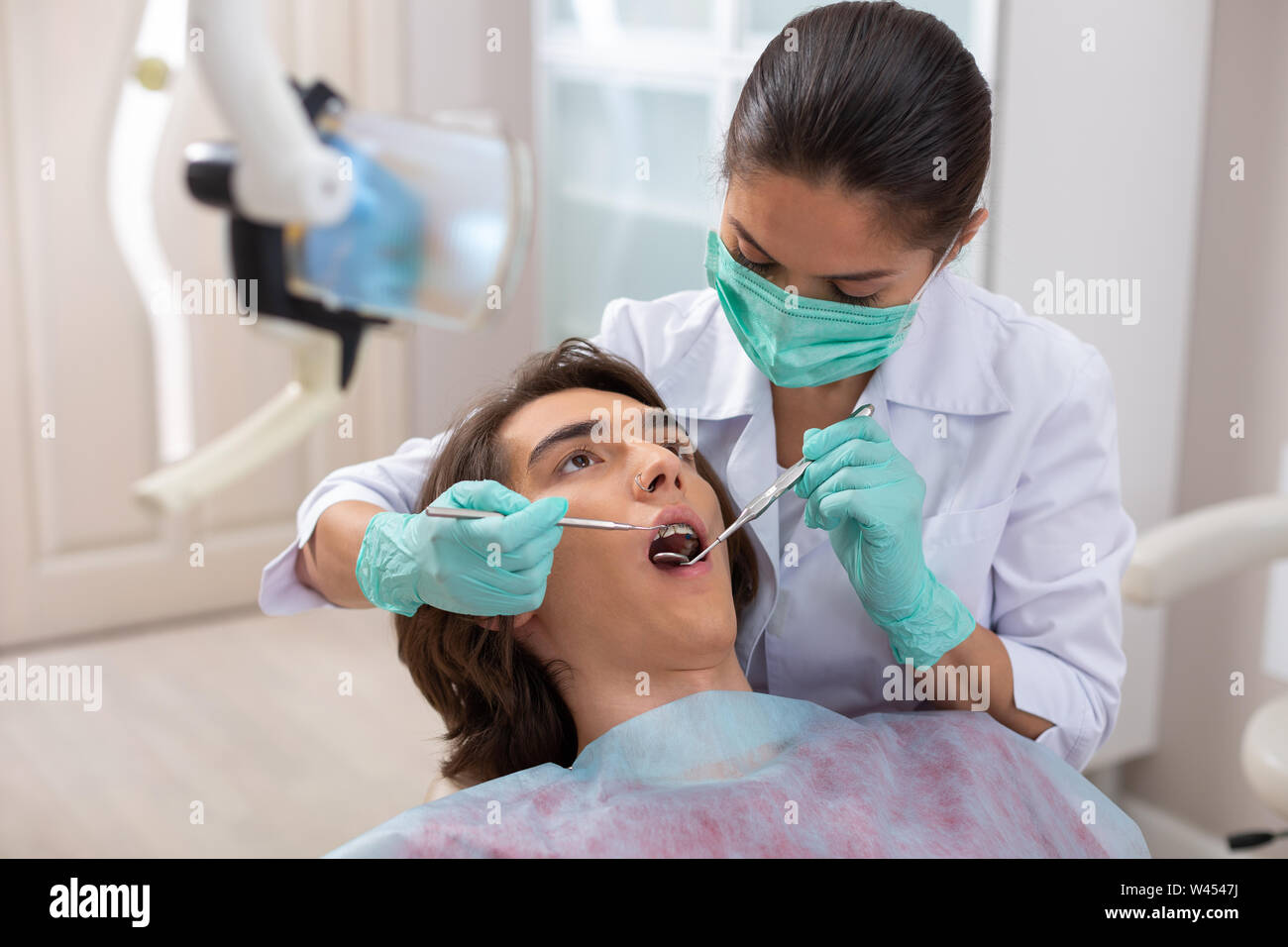 Female dentist looking in a male patients mouth Stock Photo