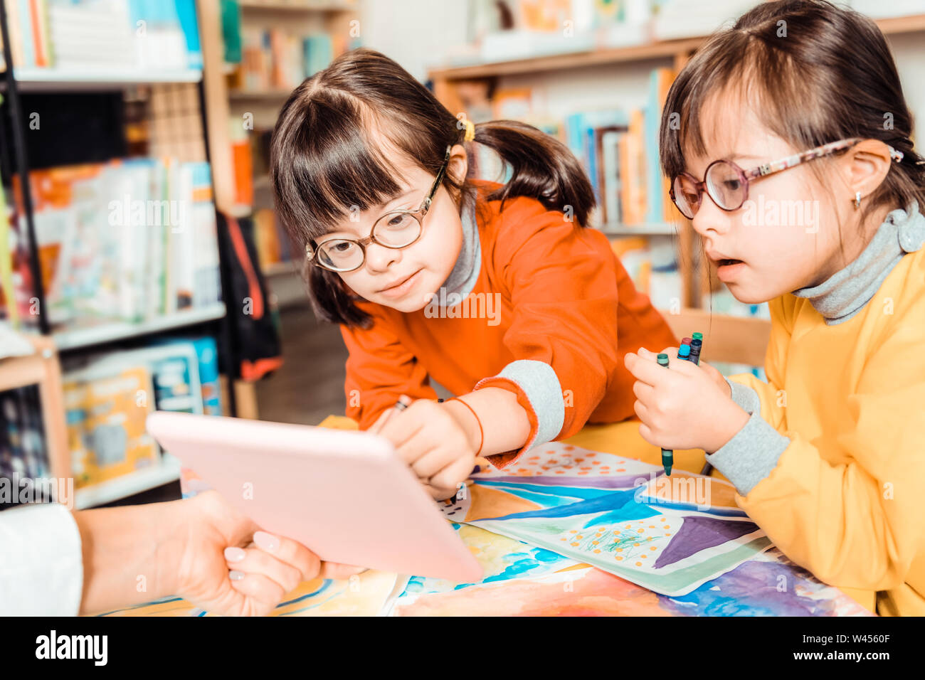Curious sisters with down syndrome being focused on a tablet Stock Photo